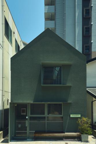 a green building with a triangle shaped roof at At Hotel ORTO in Fukuoka