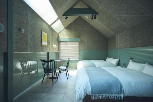 a bedroom with two beds and a table with chairs at At Hotel ORTO in Fukuoka