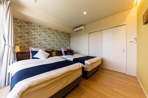 a bedroom with two beds and a sliding door at Laguna Fuchaku in Onna
