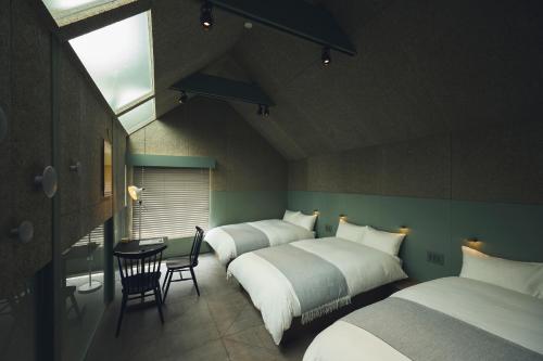 a bedroom with three beds and a table and chairs at At Hotel ORTO in Fukuoka