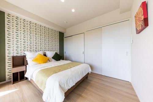 a bedroom with a large bed with a yellow pillow at Laguna Fuchaku in Onna