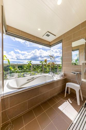 a large bathroom with a tub and a large window at Laguna Fuchaku in Onna