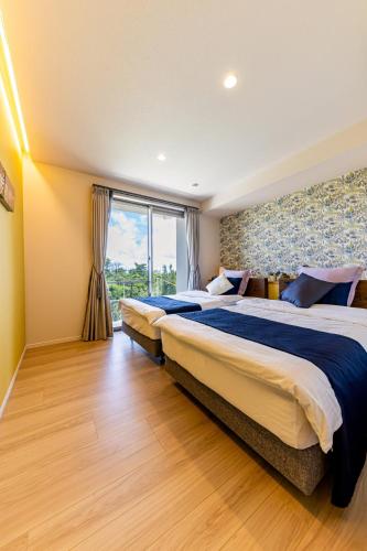 a hotel room with two beds and a window at Laguna Fuchaku in Onna