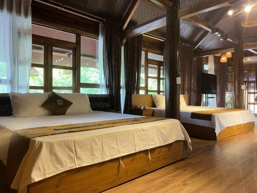 a bedroom with two beds in a room with windows at Mật Retreat in Ba Vì