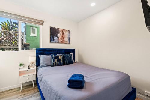 a bedroom with a bed with a blue pillow on it at 1 Block to Beach Heaven Chic 2BD in Manhattan Beach