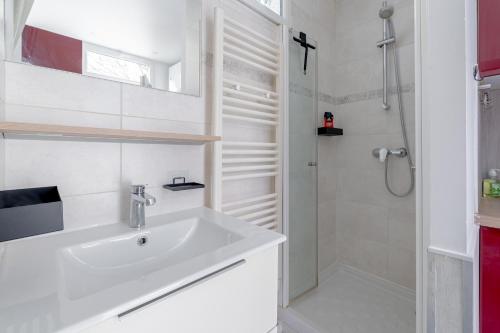 Un baño blanco con lavabo y ducha. en Charmant Studio à Saint-Mandé, en Saint-Mandé