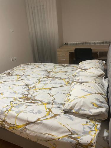 a bed with a yellow and white comforter on it at Stan na dan KM in Bukorovac