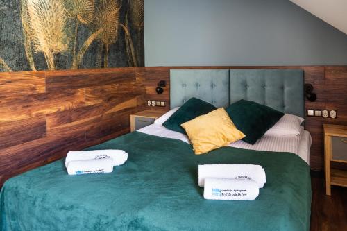 a bedroom with a green bed with towels on it at Pod Źródełkiem in Cisna