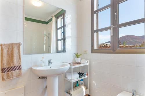 baño blanco con lavabo y ventana en Casita Dragón y Suerte Lajares Pool, en Lajares