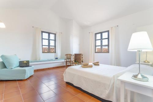 Un dormitorio con una cama, una silla y un sofá. en Casita Dragón y Suerte Lajares Pool, en Lajares