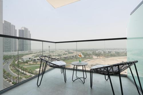 a balcony with a table and chairs and a view of the ocean at Keyrock Golf Gate - Damac Hills Apartment with Pool, Gym & Free Parking in Dubai