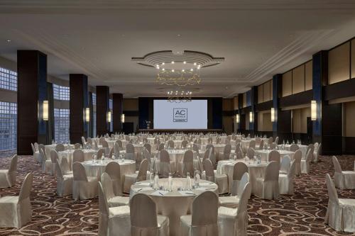 a banquet hall with white tables and chairs and a screen at AC Hotel by Marriott Ipoh in Ipoh