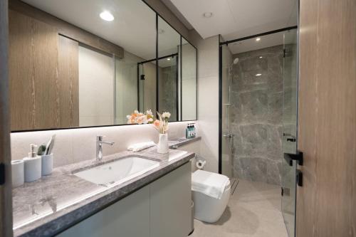 a bathroom with a sink and a toilet and a mirror at Keyrock Golf Gate - Damac Hills Apartment with Pool, Gym & Free Parking in Dubai