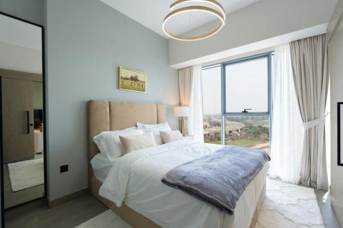 a bedroom with a large bed with a large window at Keyrock Golf Gate - Damac Hills Apartment with Pool, Gym & Free Parking in Dubai