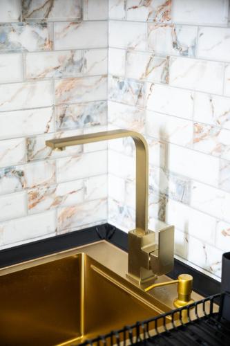 a sink in a kitchen with a marble wall at Panorama V Lux Vrnjačka Banja in Vrnjačka Banja