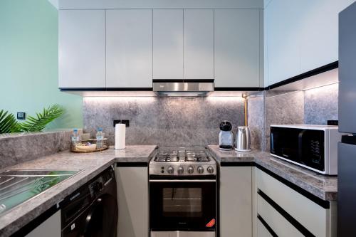 a kitchen with a stove and a microwave at Keyrock Golf Gate - Damac Hills Apartment with Pool, Gym & Free Parking in Dubai