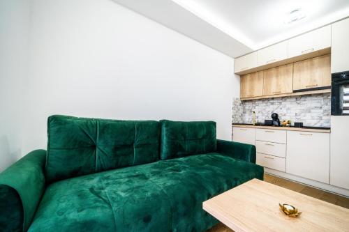 a green couch in a kitchen with a wooden table at Panorama V Lux Vrnjačka Banja in Vrnjačka Banja