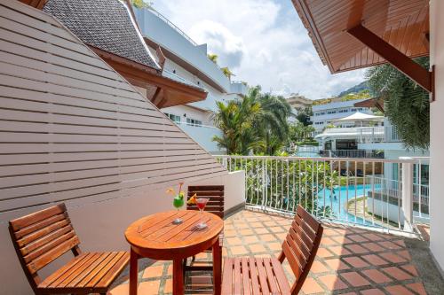 a patio with a wooden table and chairs and a pool at Phunawa Resort Phuket Karon Beach - SHA Plus in Karon Beach