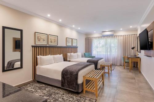 a hotel room with two beds and a desk at Park Hotel Mokopane in Mokopane