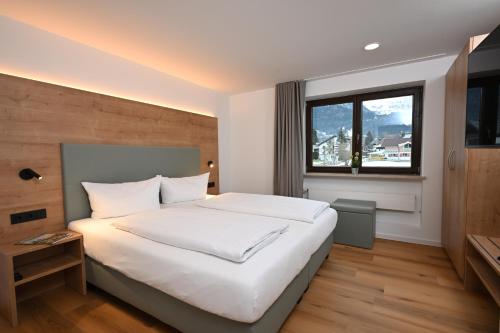 a bedroom with a large white bed and a window at Alpenhof Apartments Oberstdorf in Oberstdorf