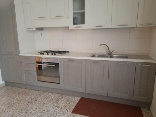 Una cocina con gabinetes blancos, un fregadero y una estufa. en Lo Studio del Pittore, en Vasto