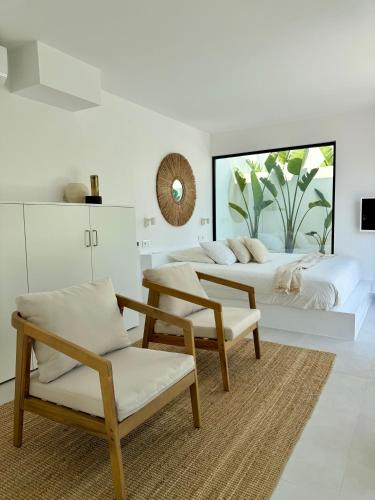 a white bedroom with two beds and a chair at EBLI7 Hotel Boutique in Orihuela Costa