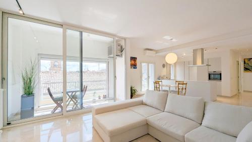 a living room with a white couch and a kitchen at Carolina Apartment in Fidenza