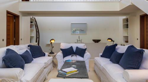 a living room with two white couches and blue pillows at Luxurious Beachfront Villa in Flamands in Anse des Flamands