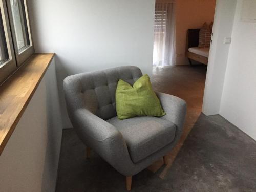 a gray chair with a green pillow in a room at Ferien- Und Winzerhof Simon in Freiburg im Breisgau