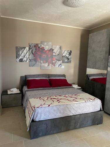 a bedroom with a bed with four paintings on the wall at Soggiorni tra Le Olive in Torre Mozza