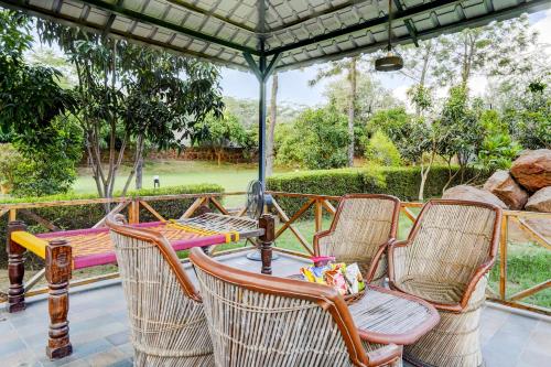 a group of chairs and a table on a porch at Alaya Stays Fortezza Pet-friendly 6-BHK Farmhouse With Private Pool, Gazebo & Lush Garden in Bhundsi