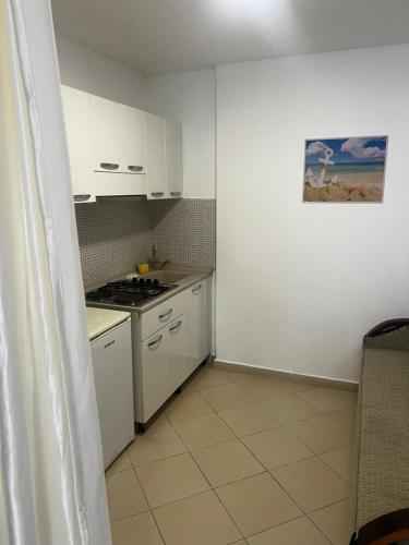 a small kitchen with white cabinets and a stove at Hotel PEJA in Velipojë