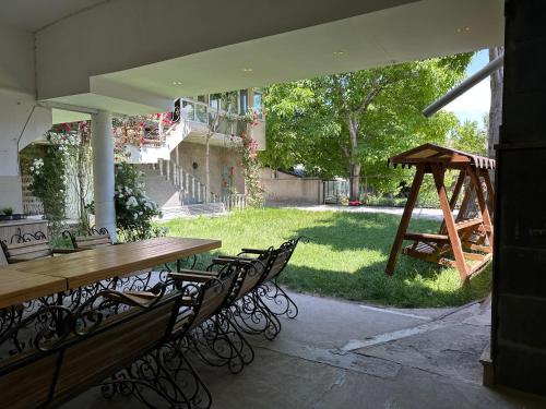 an outdoor patio with a table and chairs and a swing at TAGANI Guest House in Martuni