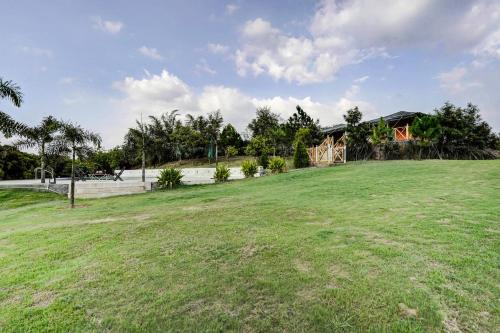 a large grass field with a house in the background at Alaya Stays Fortezza Pet-friendly 6-BHK Farmhouse With Private Pool, Gazebo & Lush Garden in Bhundsi