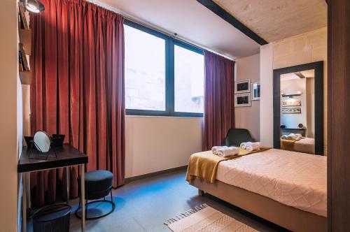 a bedroom with a bed and a desk and a window at Valletta Collection Orangerie 401 in Valletta