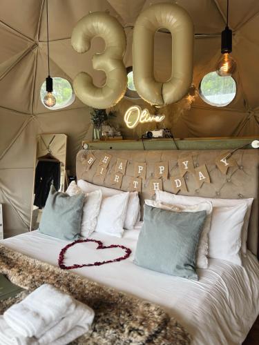 a bed in a tent with a sign above it at Beautiful Olive Pod Geo Dome House with Hot Tub in East Horsley