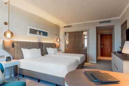 a hotel room with two beds and a table at Hilton Diagonal Mar Barcelona in Barcelona
