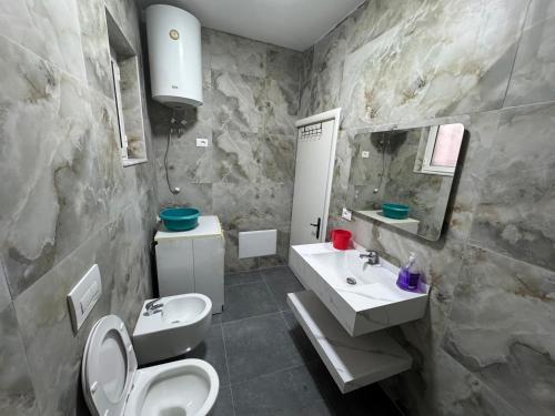 a bathroom with a sink and a toilet and a mirror at Green Escape Apartment Tirana in Tirana