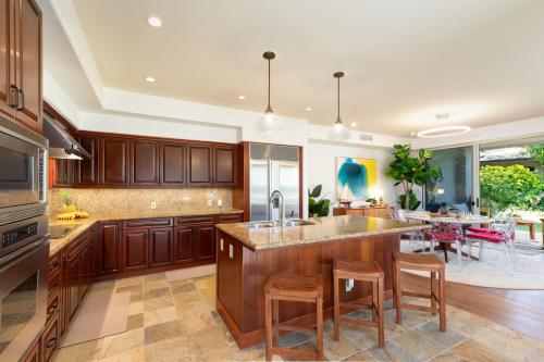 a kitchen with wooden cabinets and a large island with bar stools at ❤PiH❤ Aloha Joes Ohana Close to Beaches and Restaurants in Waikoloa