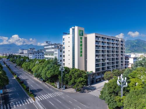 a tall white building with a green sign on it at Holiday Inn Express Lijiang Ancient Town by IHG in Lijiang