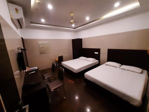 a hotel room with two beds and a table and chairs at KJR Residency in Chennai