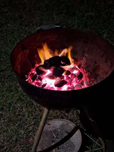 a bbq grill with fire in it on the grass at Le Pavillon, at La Petite Ferme 2BRoom with private fireplace in Grand Sable