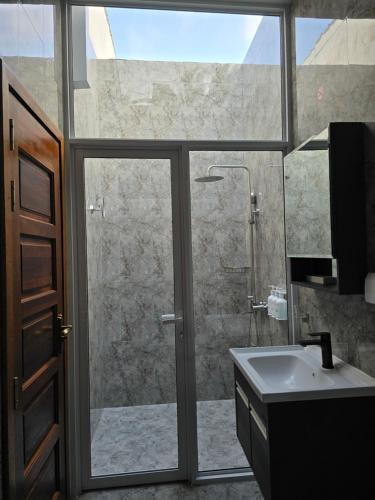 a bathroom with a shower and a sink and a window at Dhonfalhu Dhigurah in Dhigurah