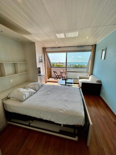 un grand lit dans une chambre avec une grande fenêtre dans l'établissement Studio avec terrasse - Vue océan, à La Rochelle