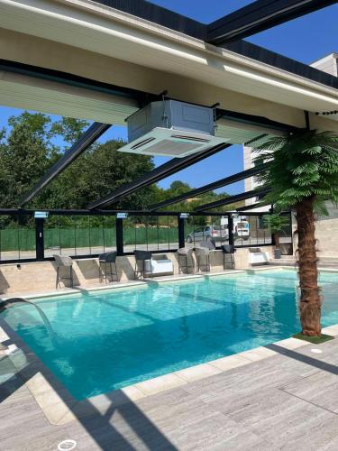 a swimming pool with awning and a palm tree at Panorama V Lux Vrnjačka Banja in Vrnjačka Banja
