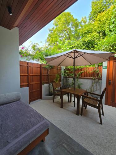 a patio with a table and an umbrella at Dhonfalhu Dhigurah in Dhigurah