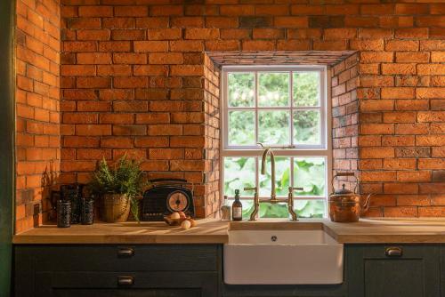 a kitchen sink and a window in a brick wall at The Forest at Mount Congreve Gardens in Kilmeaden