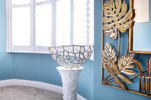 a blue room with a white vase and a mirror at Ladybird House in Loughborough