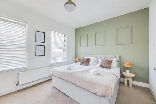 Un dormitorio blanco con una cama grande y dos ventanas. en Lutterworth House - Prime Location - Free Parking, Pool Table, Fast WiFi and Smart TV by Yoko Property, en Northampton
