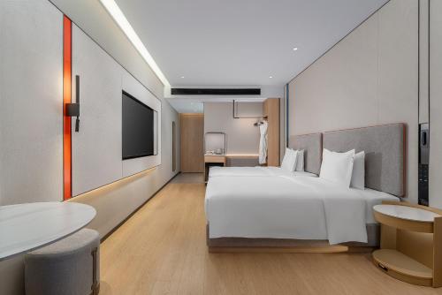 a hotel room with a large white bed and a television at Holiday Inn Express Lijiang Ancient Town by IHG in Lijiang